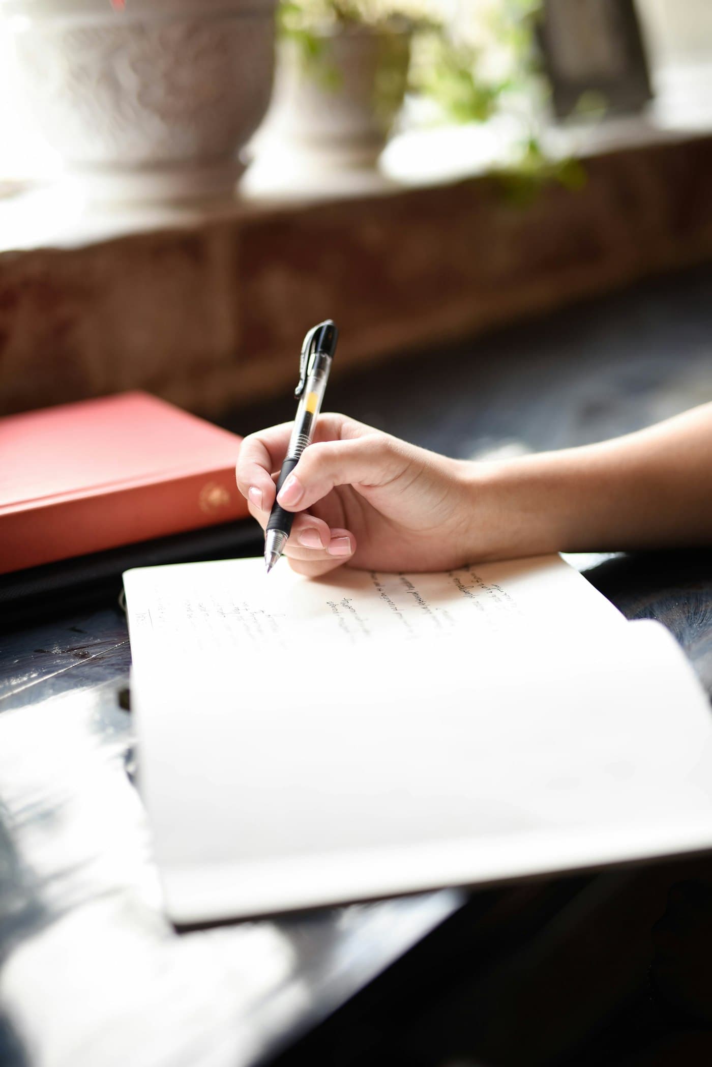 Une main qui écrit au stylo sur un document